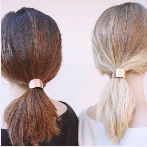 back view of brown hair and blonde hair model with medium length hair styles into low ponytails with gold hair cuffs