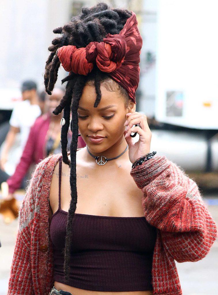close up shot of rihanna with faux dreadlocks on the set of oceans 8, wearing red top and red cardigan