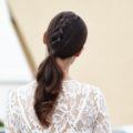 brunette model with a unicorn braid ponytail wearing a white lace top