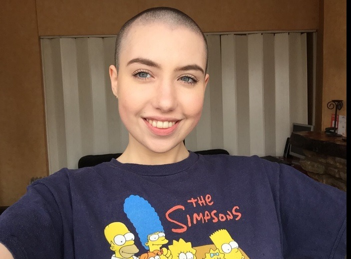 woman with a shaved head taking a selfie wearing a The Simpsons tshirt