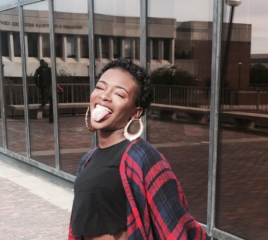 black woman with short curly hair posing with her tongue out wearing hoop earrings