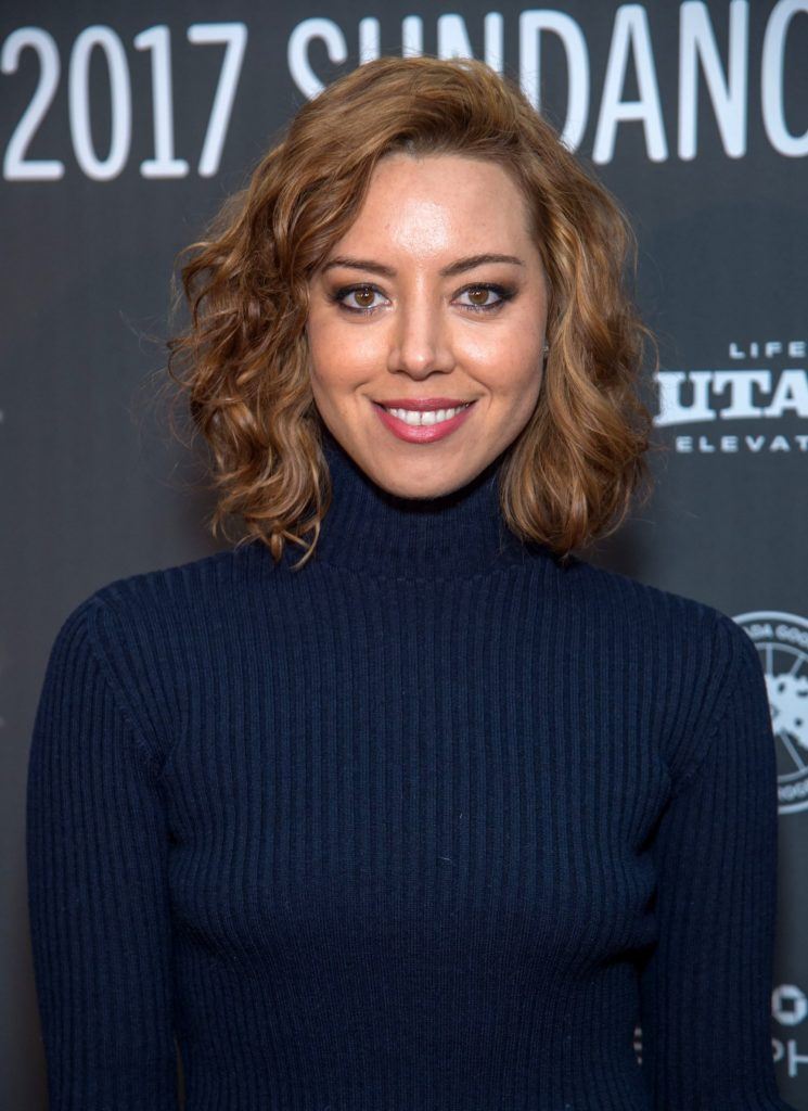Aubrey Plaza with a wavy bob ginger hairstyle on the red carpet wearing a navy roll neck jumper