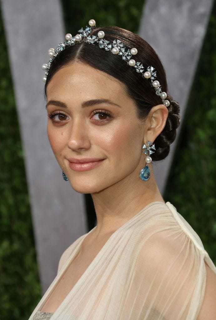 Prom hairstyles: Woman with dark brown hair in sleek low bun with a tiara pearl headband.