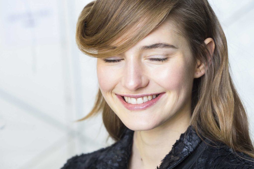 a front look of a girl smiling while closing her eyes