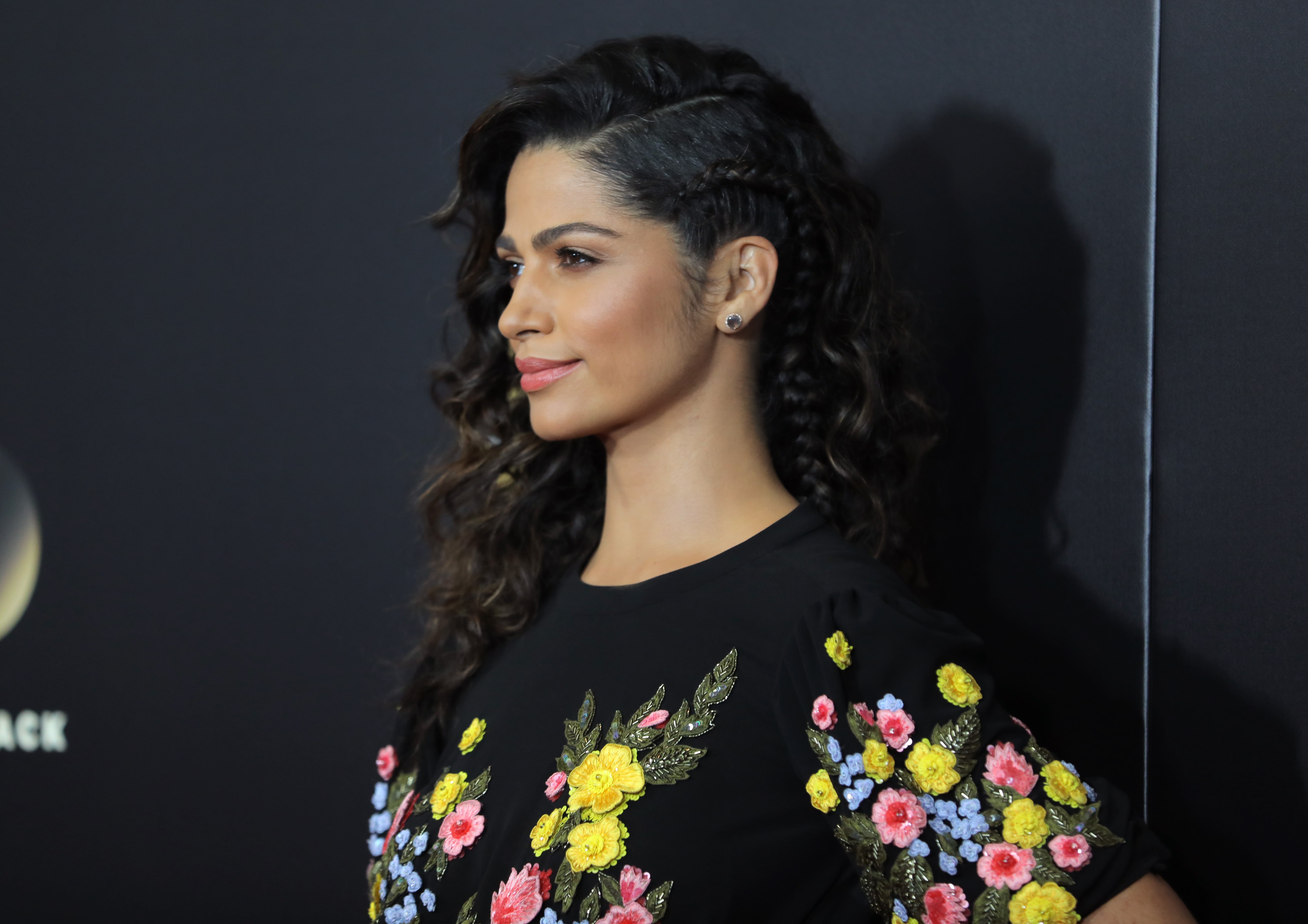 Camila Alves with a side braided curly hairstyle wearing a floral dress