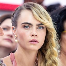 Side hairstyles: Cara Delevingne at Paris Fashion Week AW19 with long blonde hair in a side braid, wearing a pink dress
