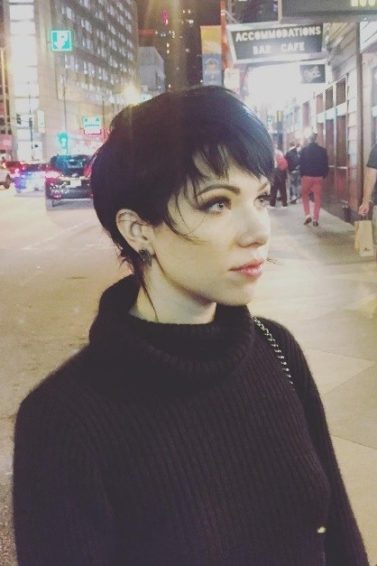 Carly Rae Jepsen with a brown long pixie shag haircut wearing all black
