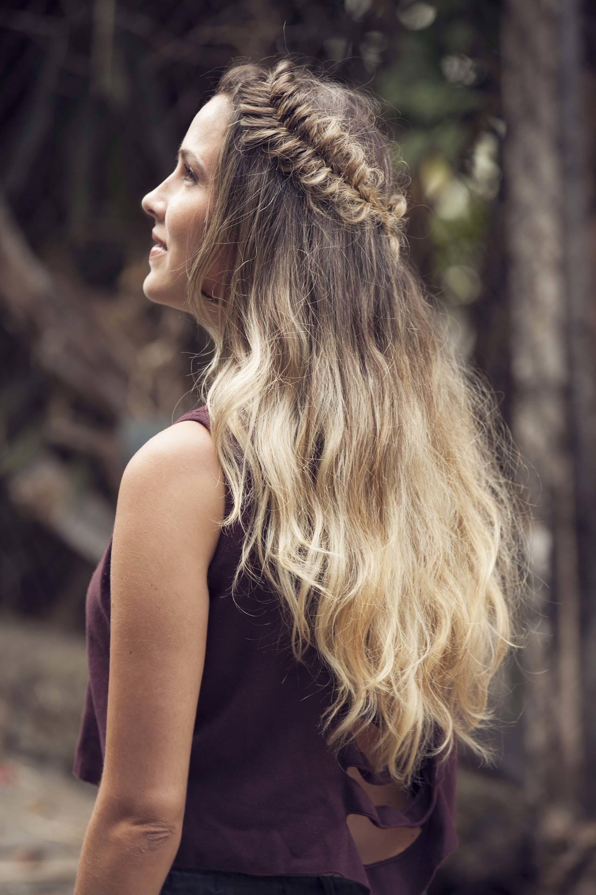 Young woman looking up with her blonde ombre hair in a half-up fishtail braid crown