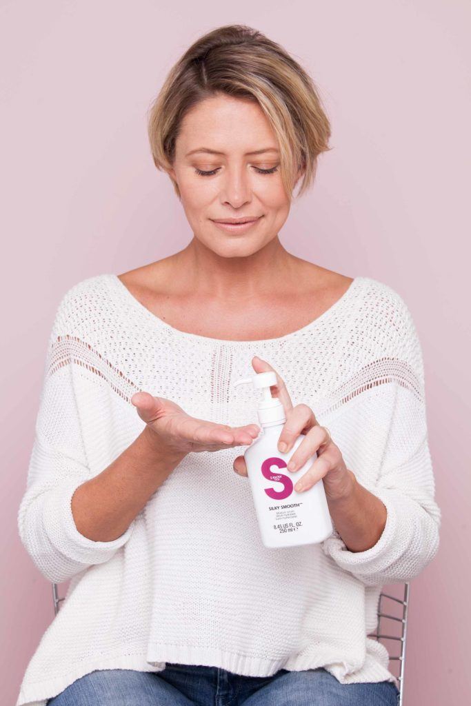 woman dispenses tigi serum on her hand before curling short hair