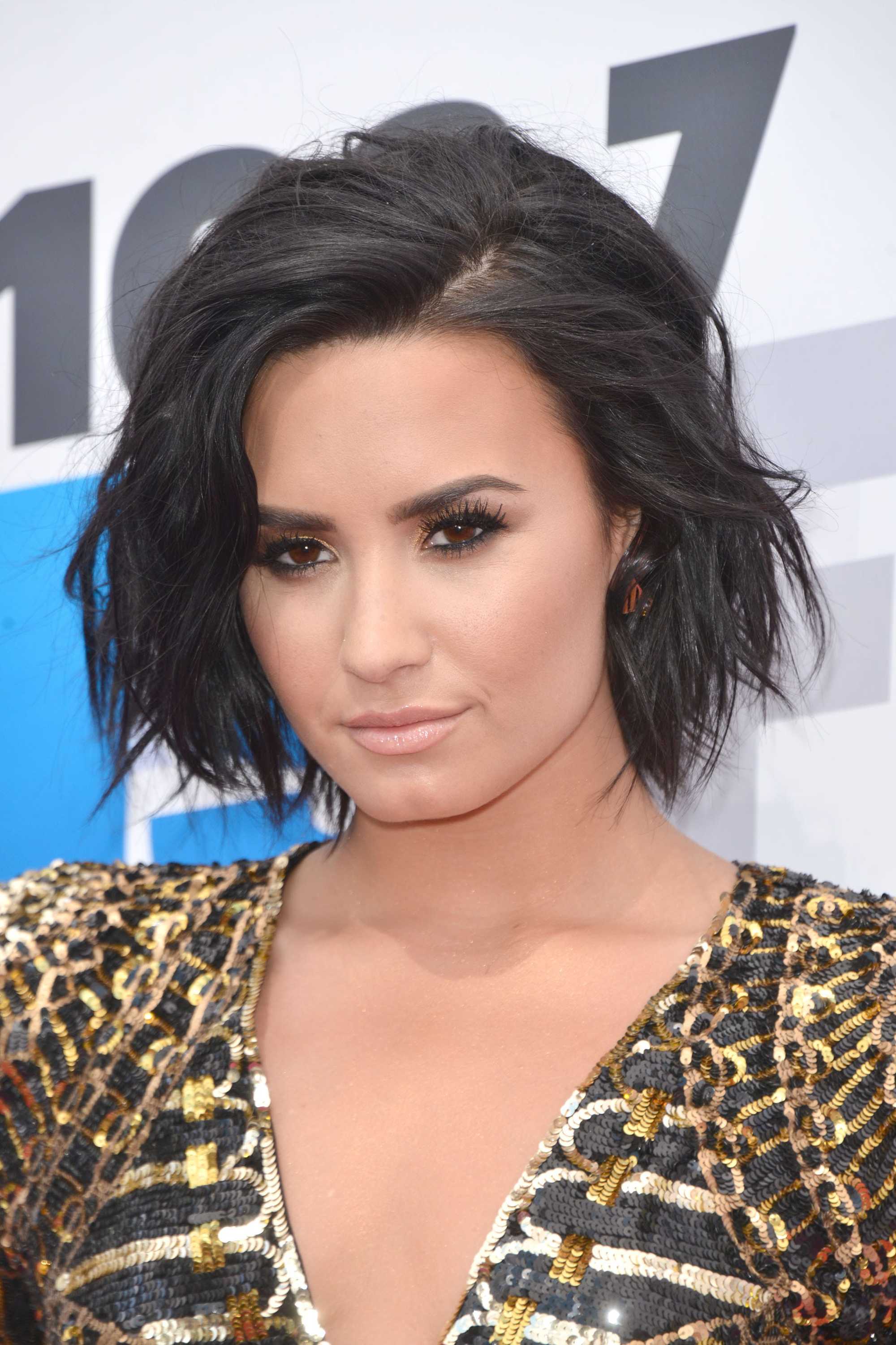 Demi Lovato with textured bob wearing gold outfit