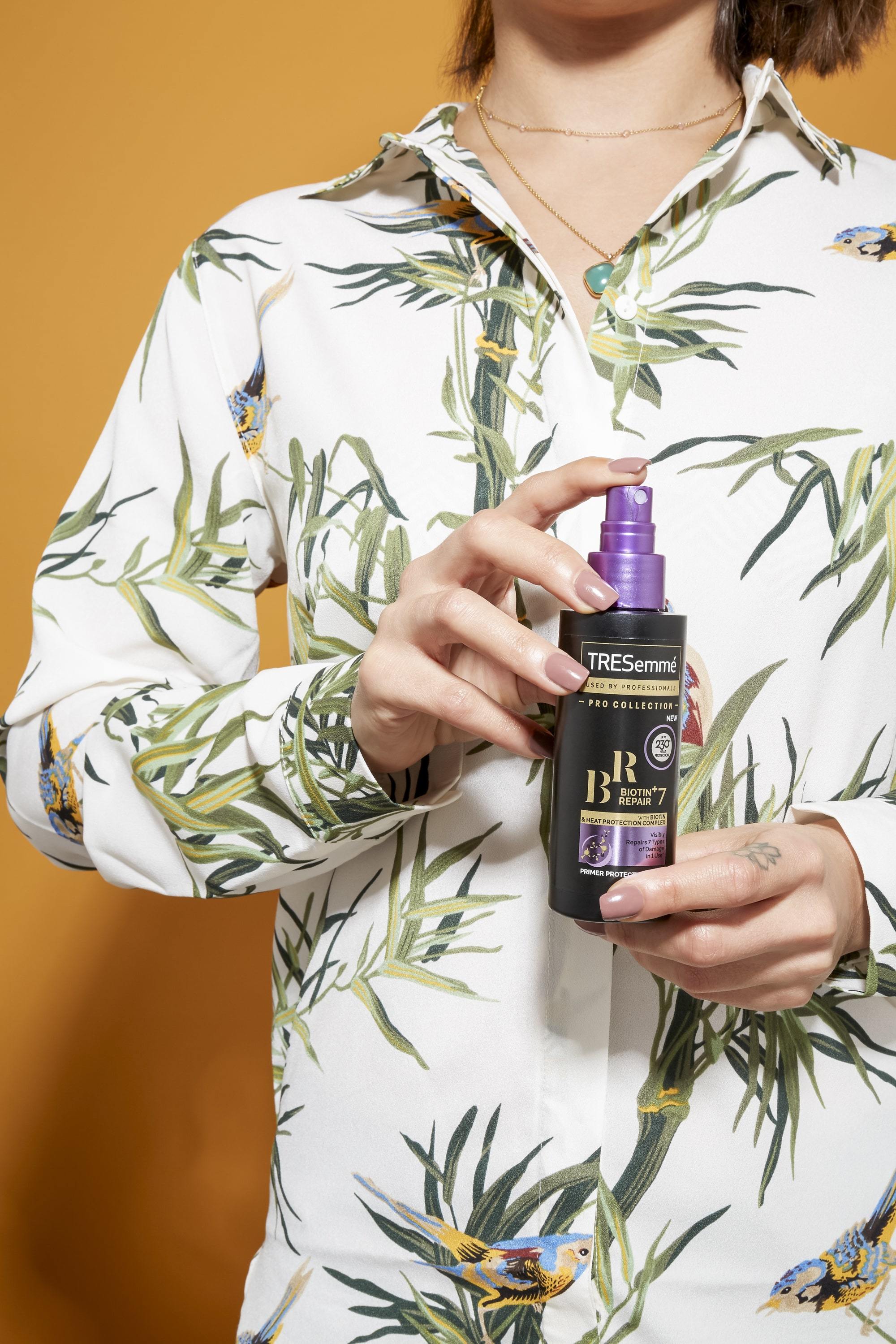 Close-up of a woman holding the TRESemmé Biotin + Repair 7 Primer Protection Spray