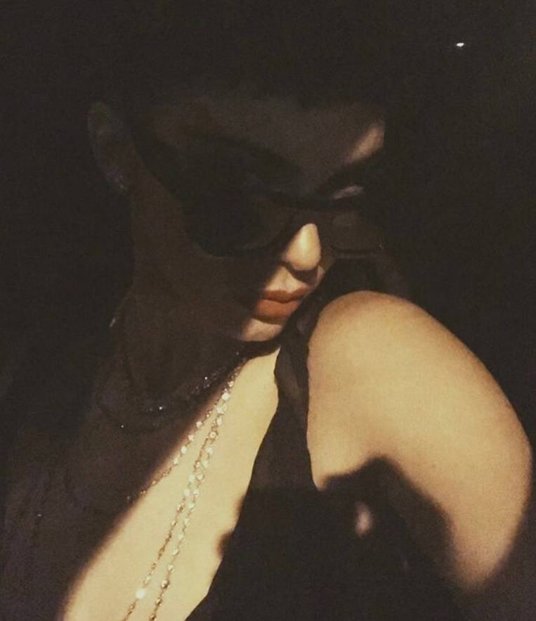 close up shot of kendall jenner with baby fringe, wearing red lipstick and black top, wearing jewellery