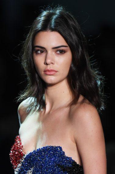 Kendall Jenner with dark shoulder length hair walking on the runway