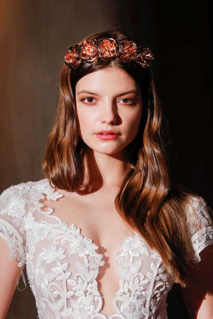 Prom hairstyles: Woman with long wavy auburn brown hair wearing a red tiara headband and a wedding dress