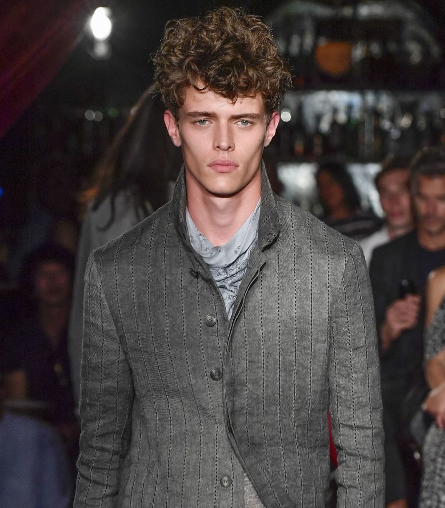 brunette male model on the catwalk with permed hair