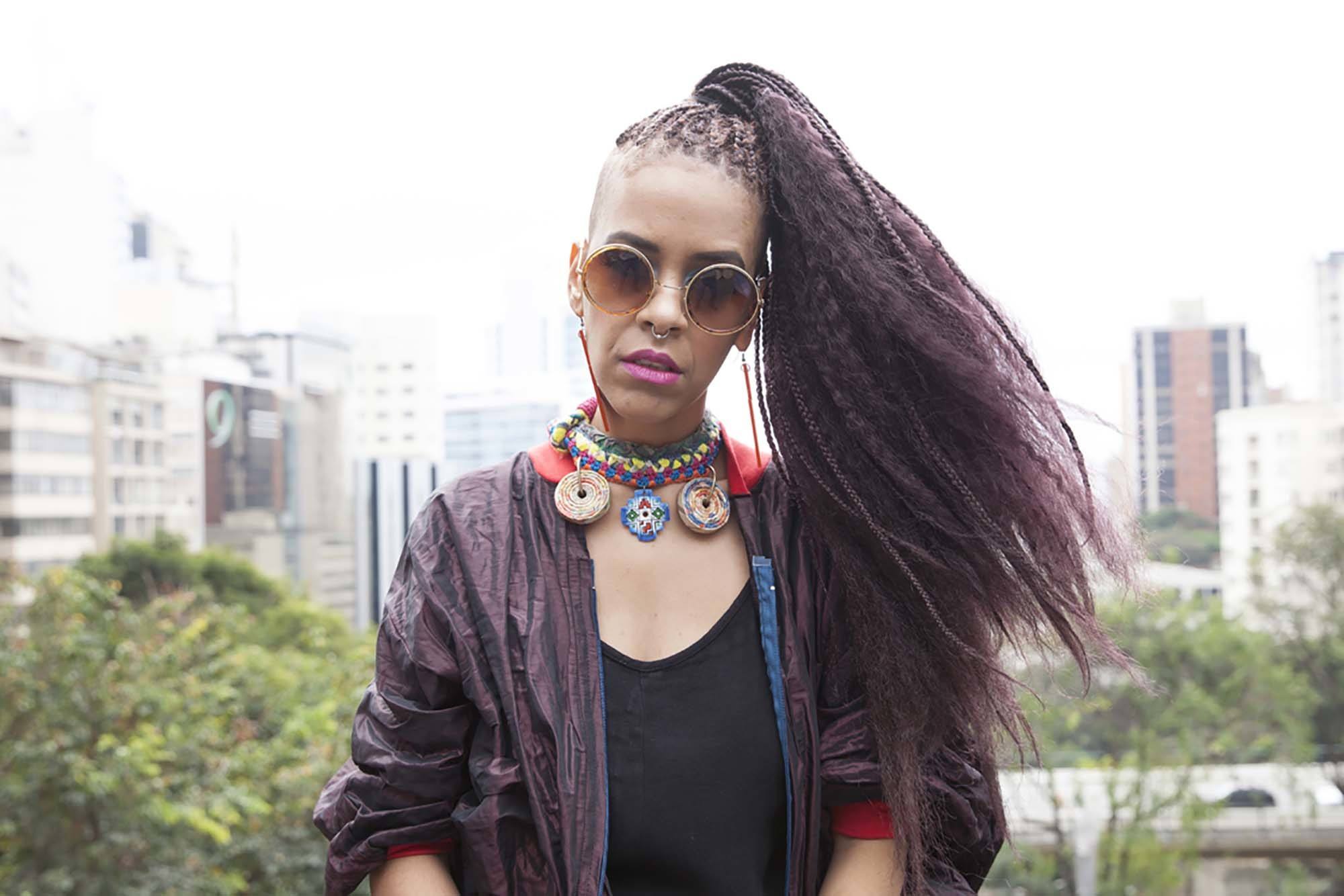 A black woman with long braids and curls wearing sunglasses