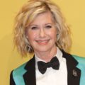 Close up of Olivia Newton John with curly bob hairstyle in teal suit
