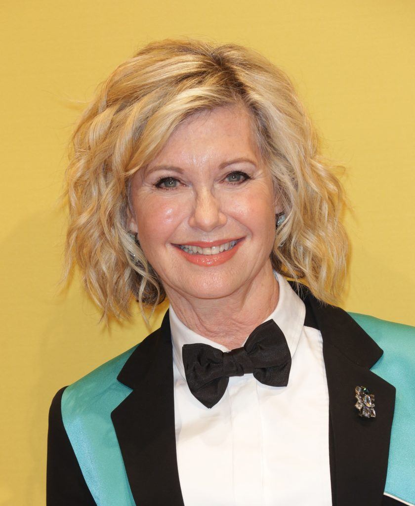 Close up of Olivia Newton John with curly bob hairstyle in teal suit