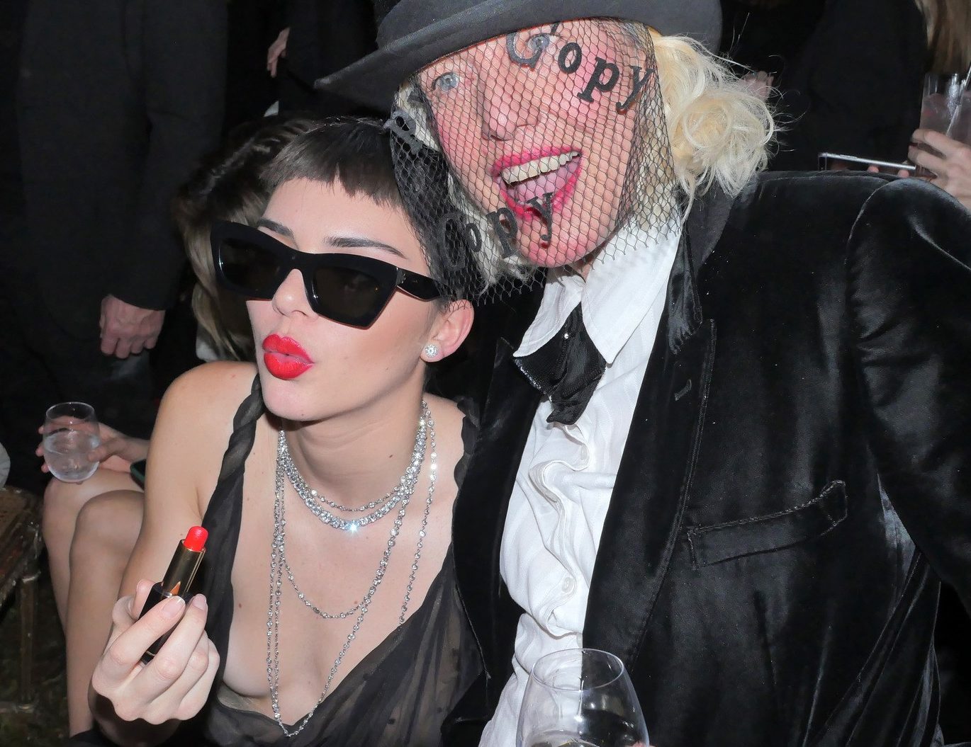 close up shot of kendall jenner and guest, with micro fringe and sunglasses, with red lipstick and black slip dress