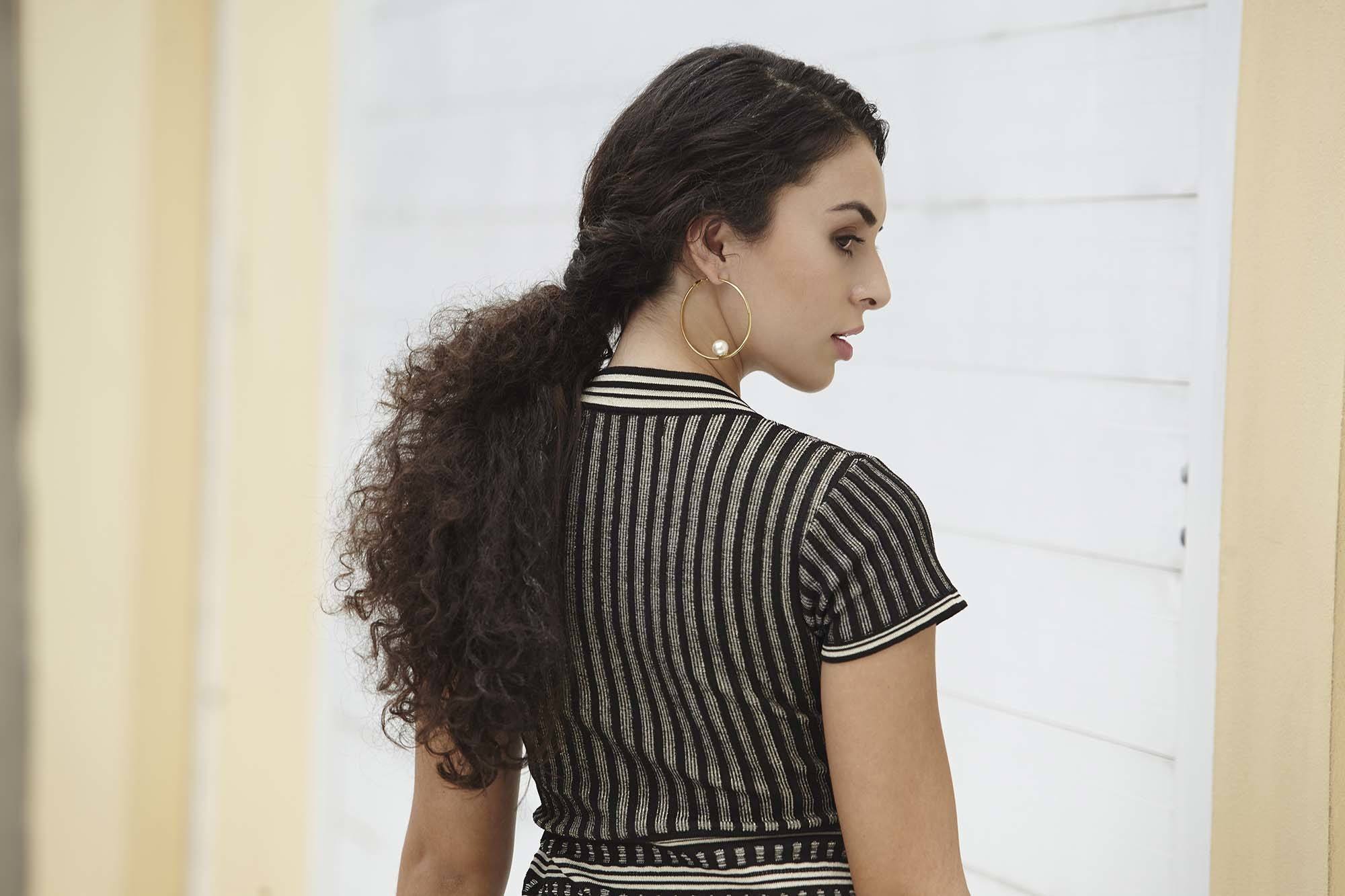 Brunette model with long curly hair in a low twisted ponytail