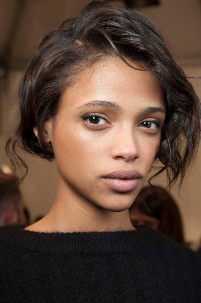 Prom hairstyles: Woman with dark brown wavy hair pinned back wearing a black jumper.