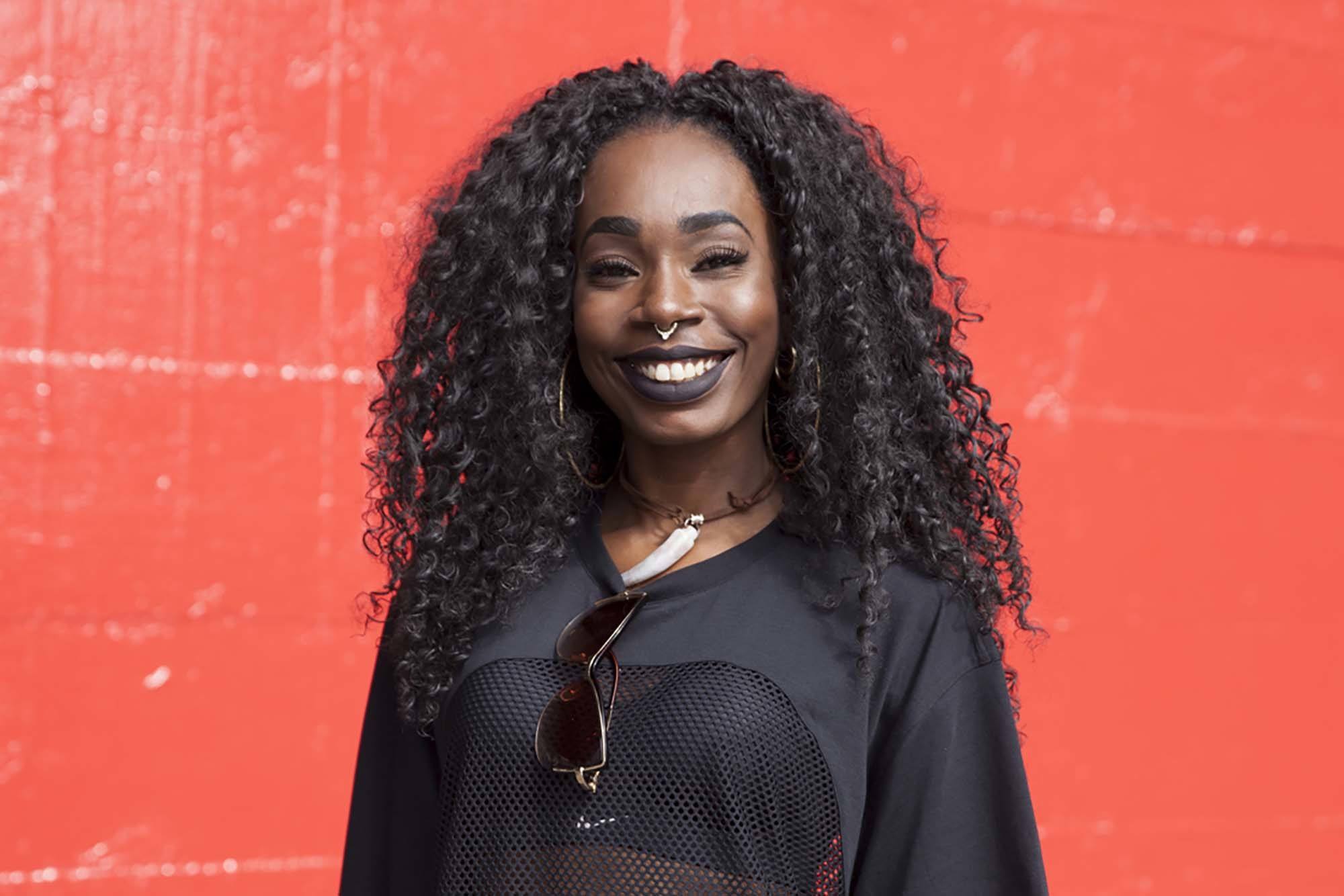 A young black woman with curly weave hairstyle wearing a dark lipstick