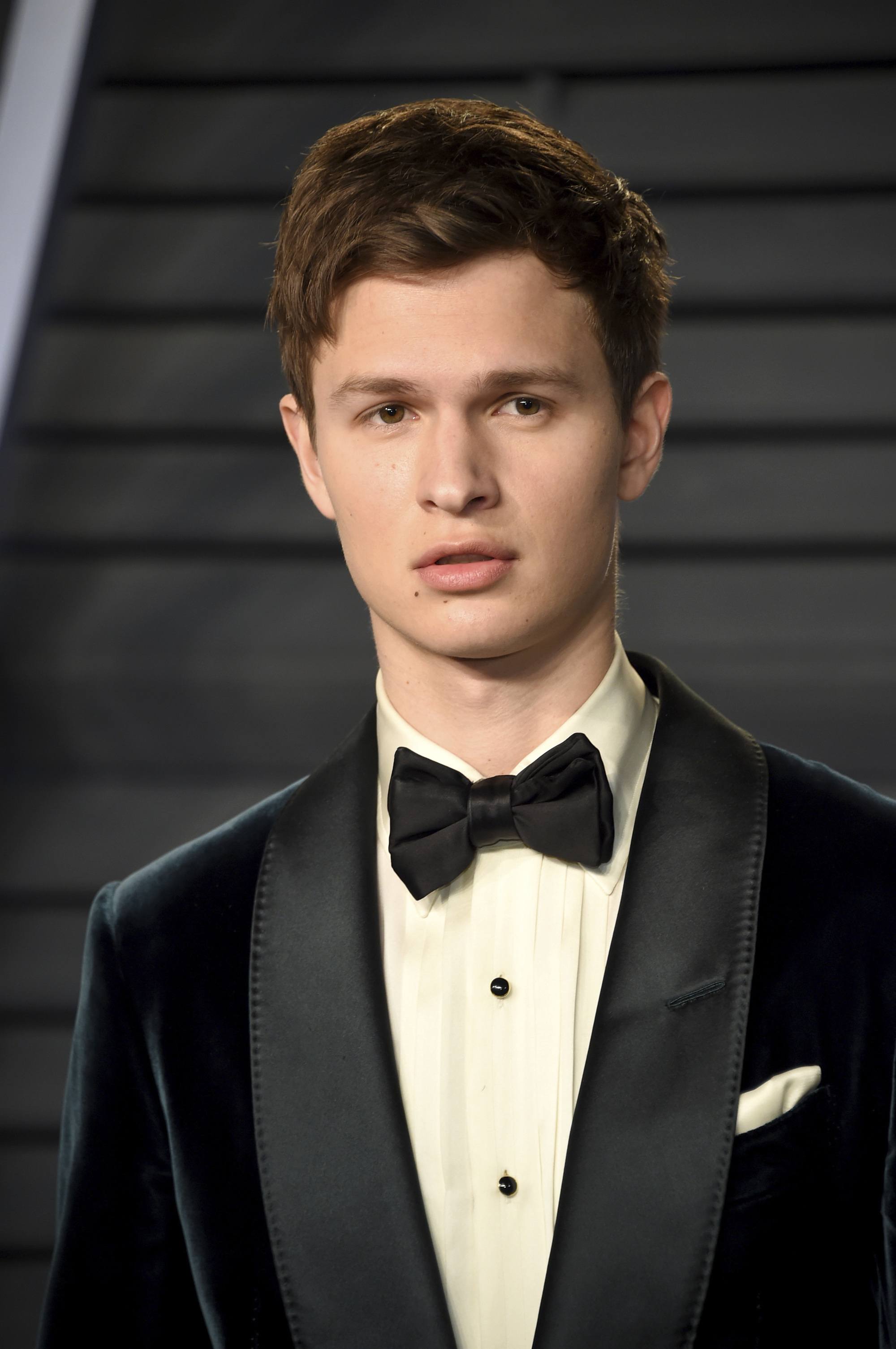 close up shot of ansel elgort wearinhg black suit with bow tie, with his hear styled into a textured mid length crop at the 90th Academy Awards