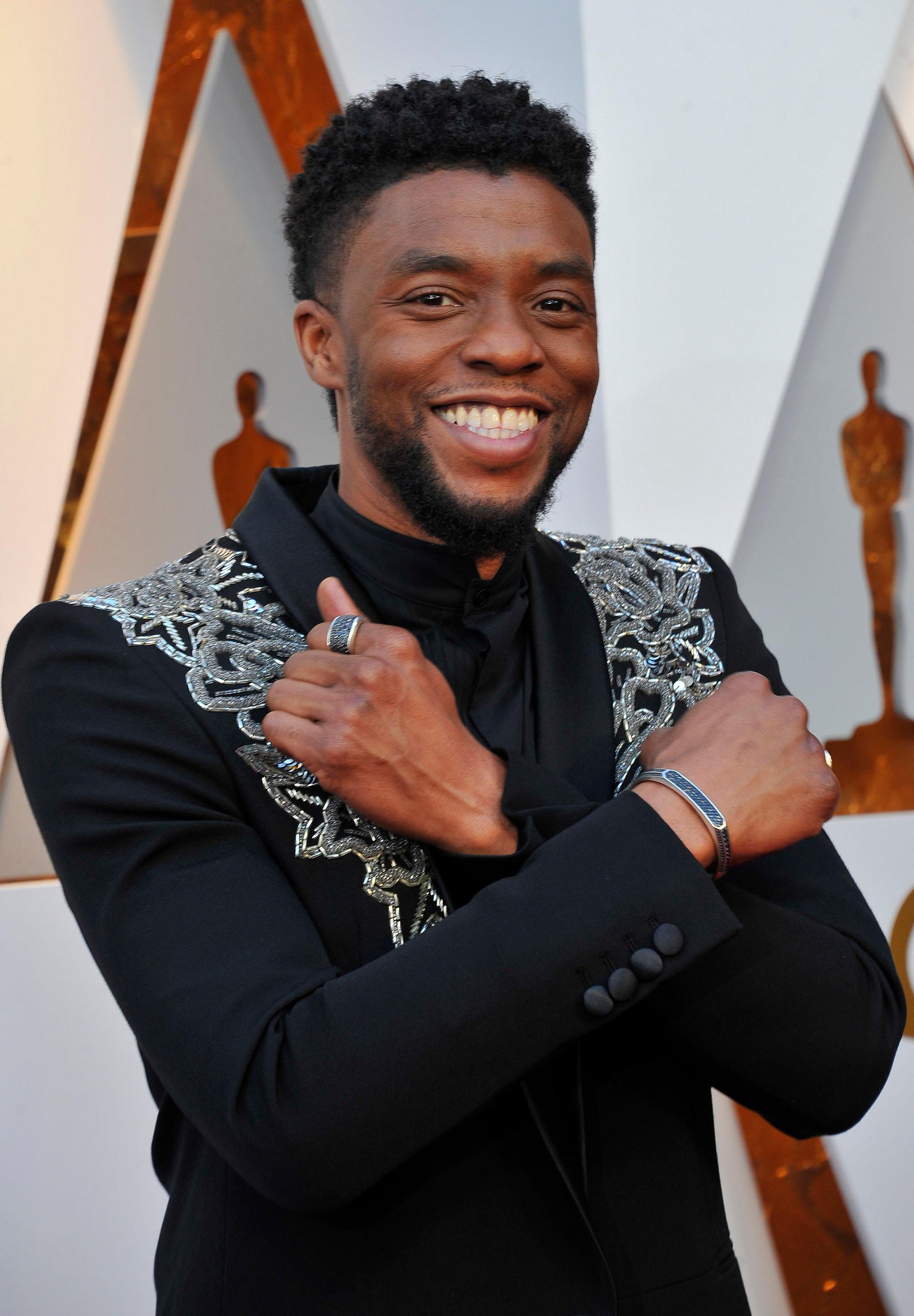 close up shot of chadwick boseman with black suit with silver designs on it wearing his black hair short in a south of france haircuit and posing at the 90th Academy Awards
