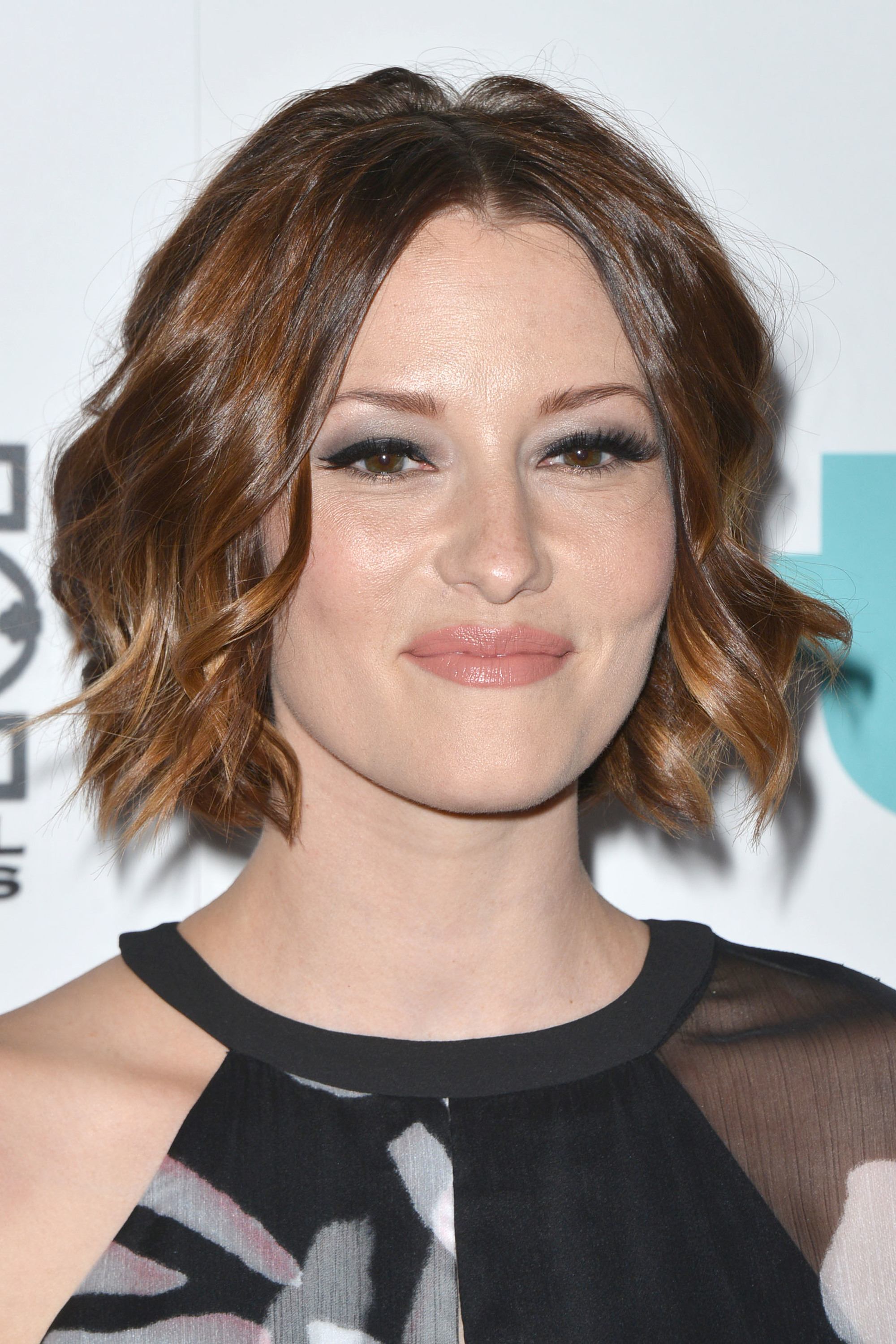 chyler leigh wearing a one shoulder halterneck black dress with bouncy balayage hair