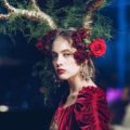 model with floral headpiece at the Dolce & Gabbana couture show wearing a red velvet dress and golden accessories