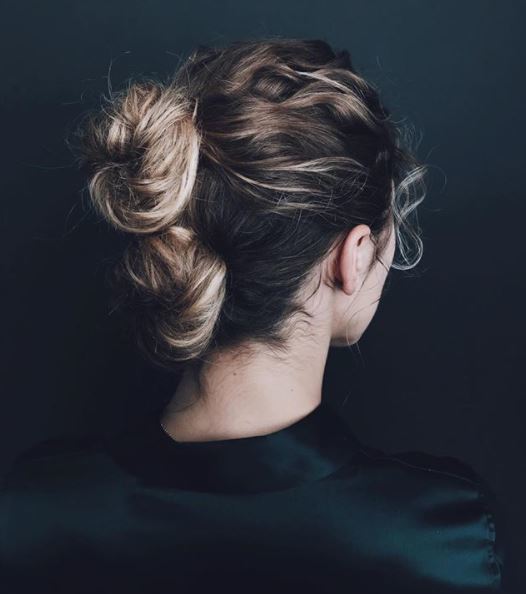 Gym hairstyles for thick hair: Back view of a woman with brown blonde ombre hair in two double stacked buns