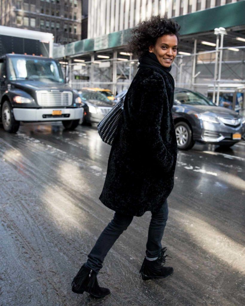 nyfw street styler in an all black outfit with dark curly hair
