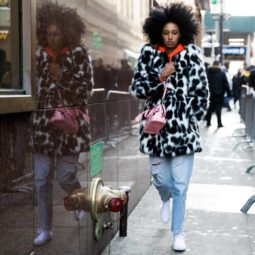 nyfw street styler wearing a spotty animal print fur coat, an orange hoodie, mom jeans and converse with voluminous natural afro hair