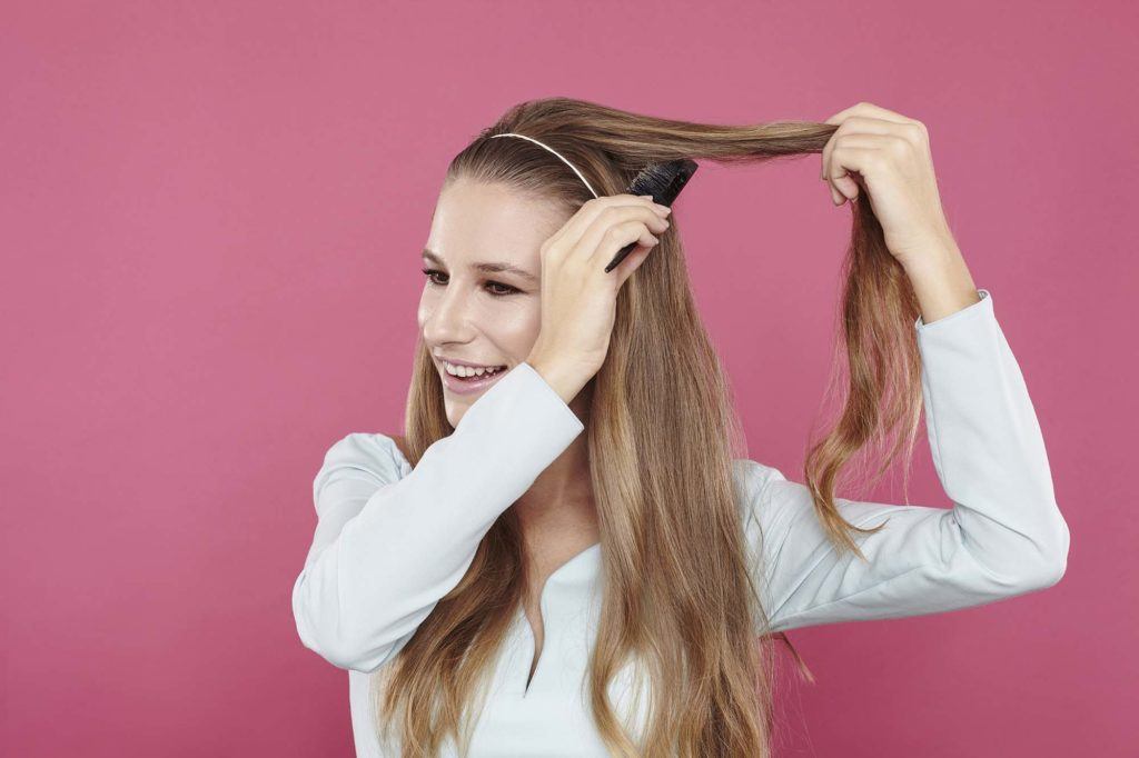 girl backcombing her long brown hair