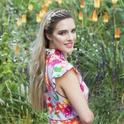 woman with long blonde hair and a headband braid wearing a floral dress outdoors