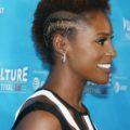 close up shot of issa rae with short frohawk hairstyle, wearing striped dress and posing on the red carpet