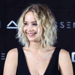 jennifer lawrence on the red carpet in a black v neck dress with blonde curly short bob hair