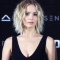 jennifer lawrence on the red carpet in a black v neck dress with a blonde shaggy lob hairstyle