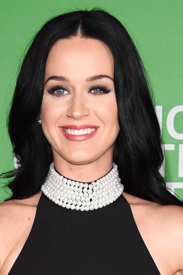 Katy Perrt wearing all black and a jewelled necklace with long dark hair