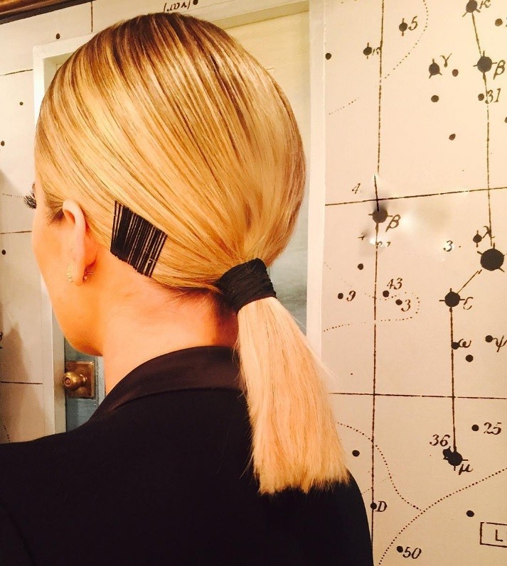 Gym hairstyles for thick hair: Close-up back view of Khloe Kardashian with blonde hair in a low sleek ponytail with bobby pin details