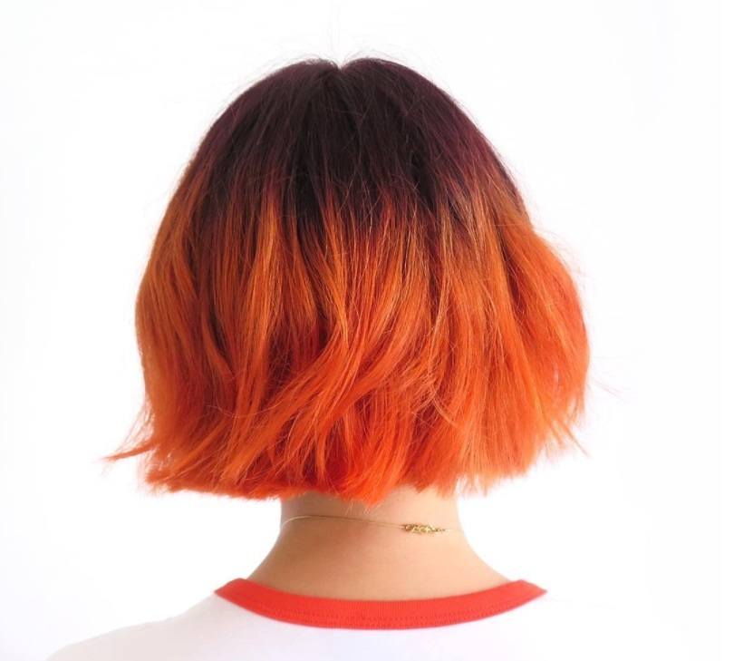 short ombre hair: model with citrus coloured orange hair and short choppy bob wearing a white t-shirt with red piping