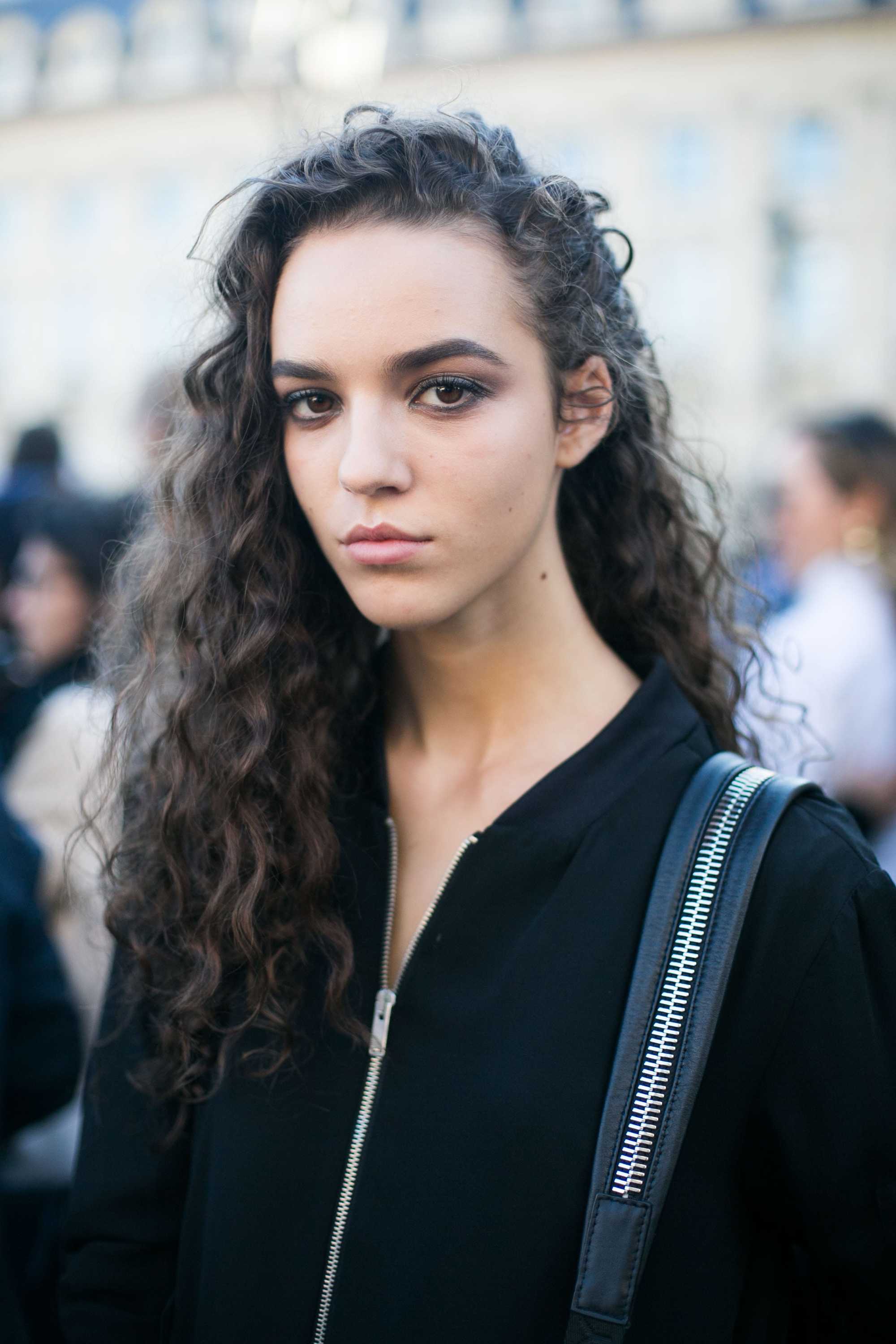 model with long curly hair wearing black