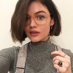 Lucy Hale with a short bob and brown hair wearing oversized glasses