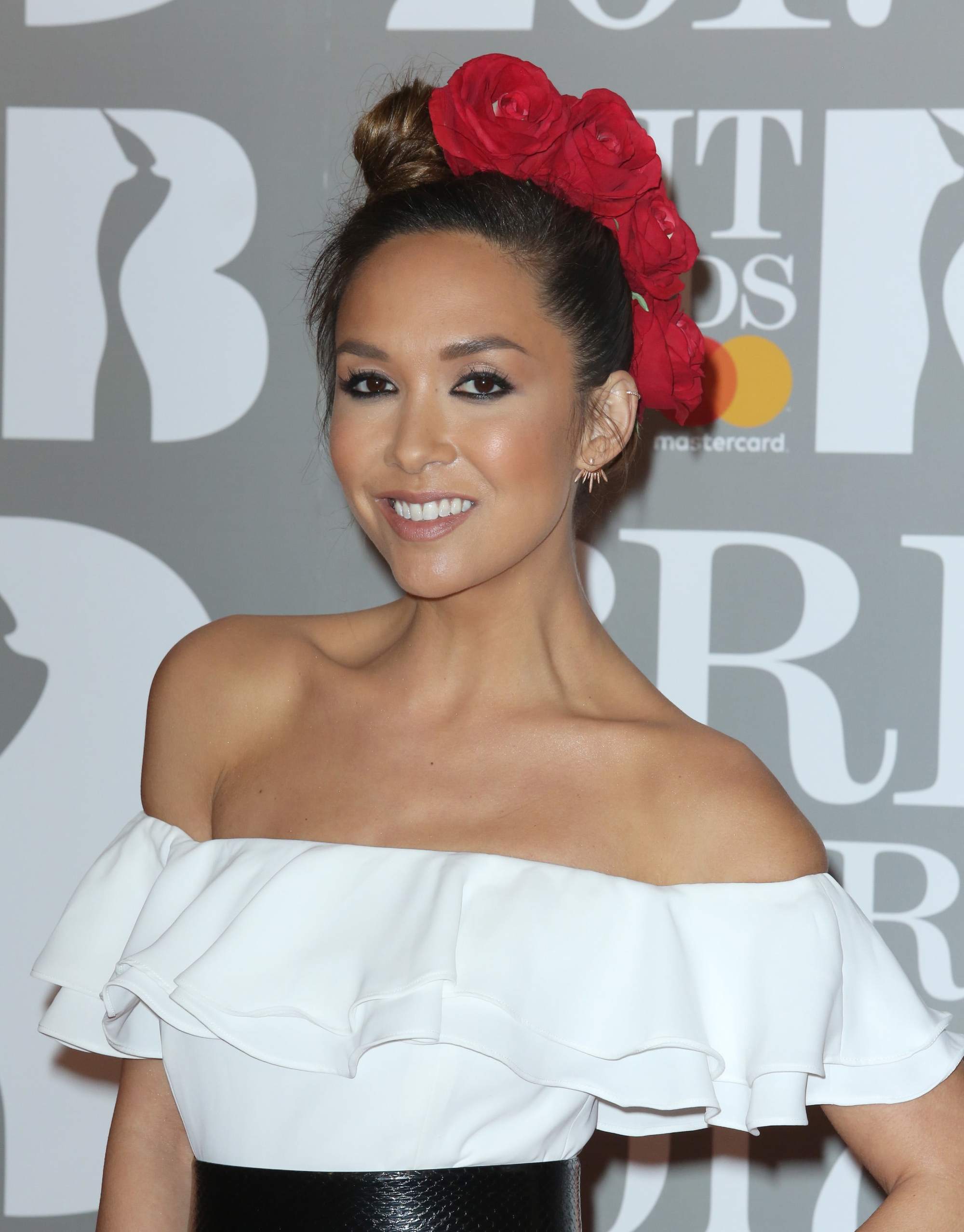 close up shot of myleene klass with floral updo hairstyle, wearing white dress and belt on the brit 2017 awards red carpet