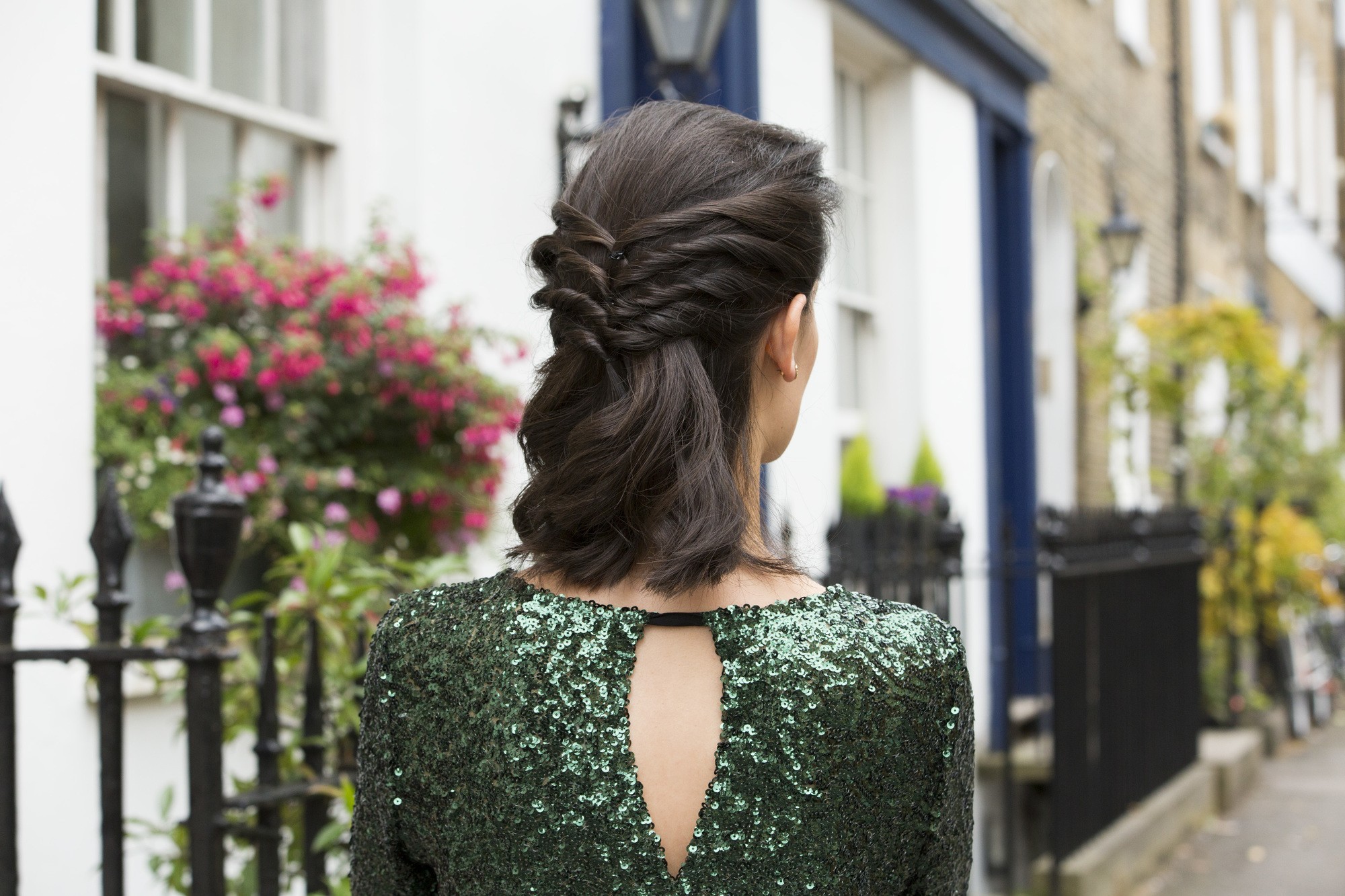 close up shot of woman with twisted half up half down hairstyle, wearing glittering dress and posing outside