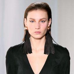 brunette model on the runway with a long bob hairstyle worn sleek, wearing a black outfit and big statement earrings