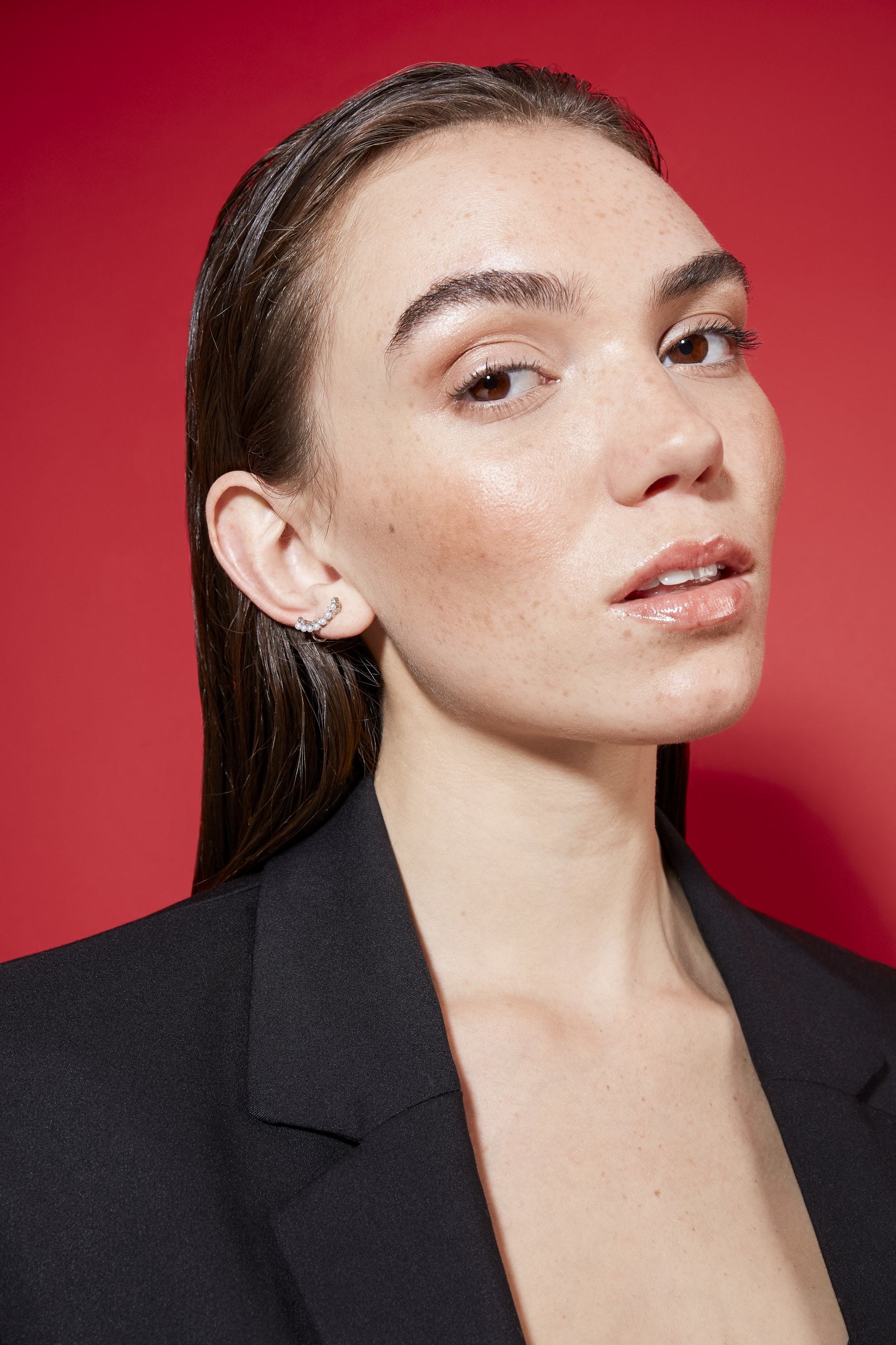 close up shot of model with slick back hairstyle, wearing black jacket and posing in a studio