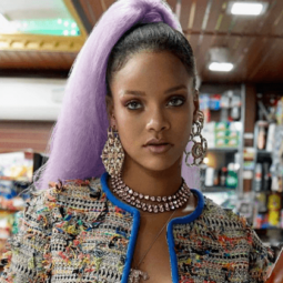 rihanna wearing big jewellery and her hair styled into a long high ponytail with a bright purple colour