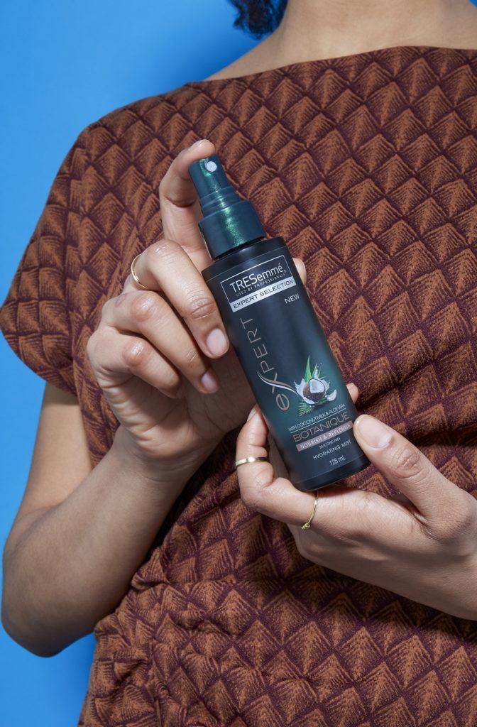 image of a woman holding a bottle of the Tresemme Botanique Hydrating Mist