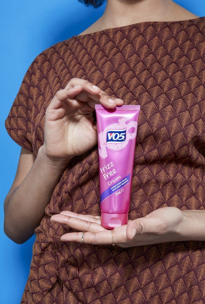 image of a woman holding a bottle of the VO5 frizz free cream
